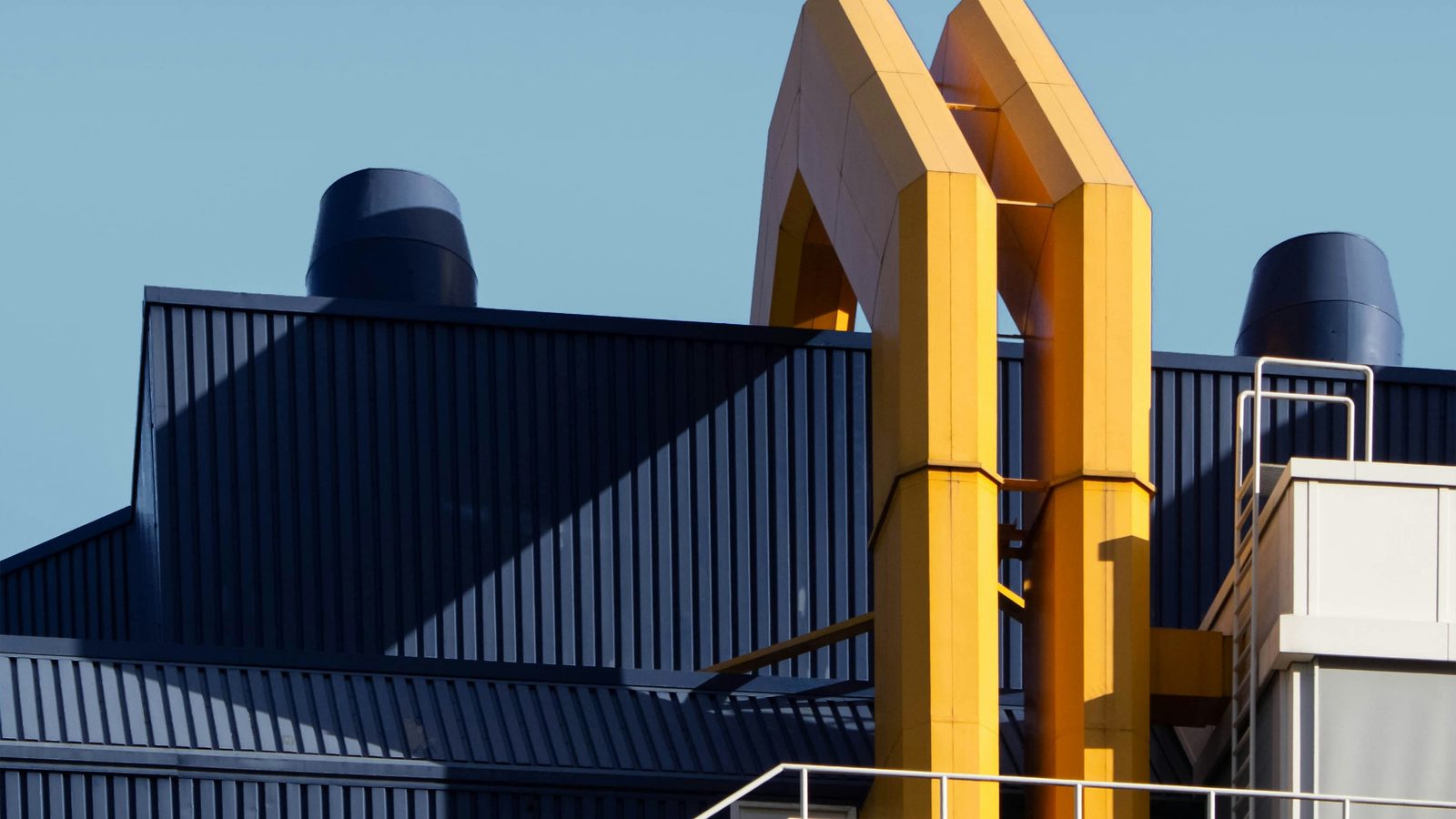 Exterior of a UK manufacturing facility with dark blue cladding and yellow architectural roofline detailing